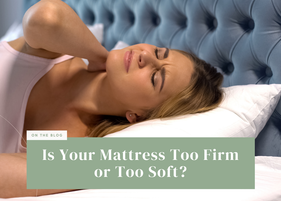 Blonde woman lying in bed grimacing while holding the back of her neck in discomfort.