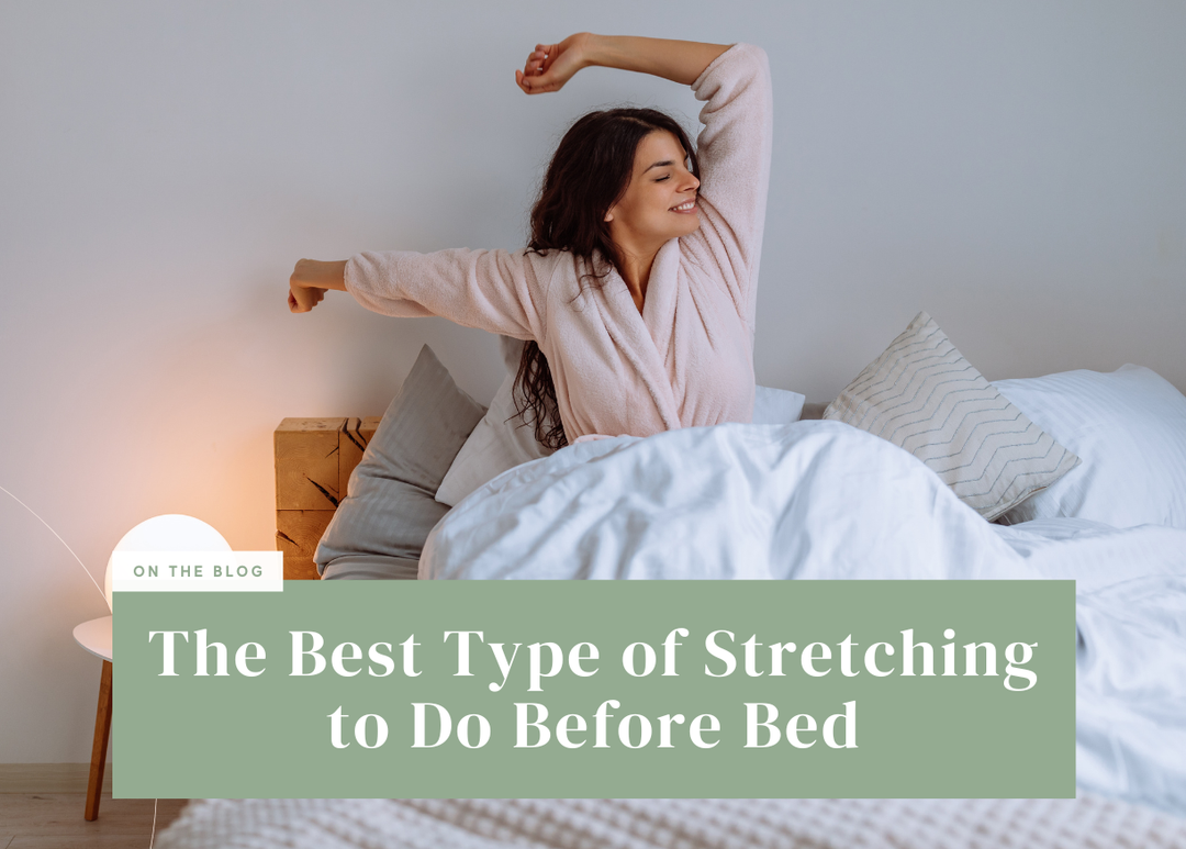 Smiling woman sitting in bed wearing a pink bathrobe stretching her arms cheerfully.
