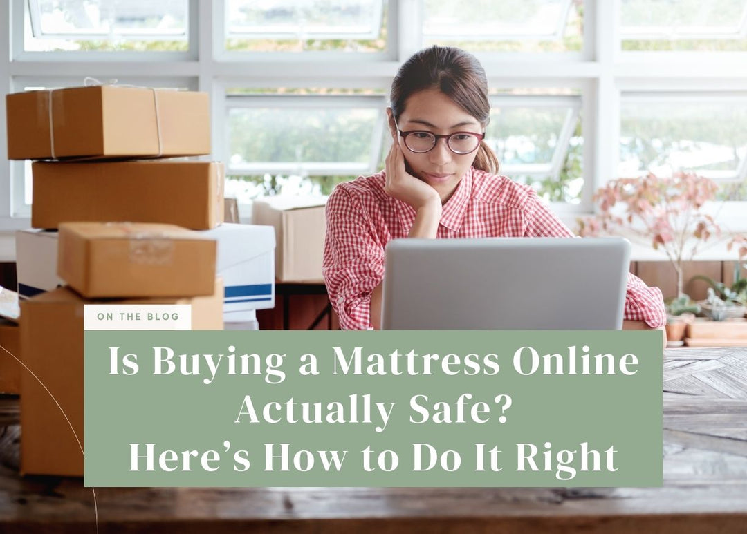 Woman wearing glasses sitting at a table with a laptop next to stacked shipping boxes.