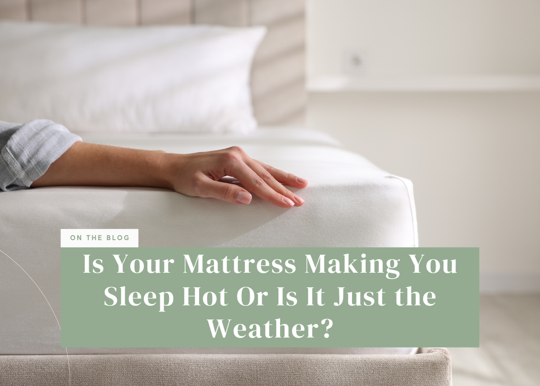 Hand resting on a white mattress with pillows in the background