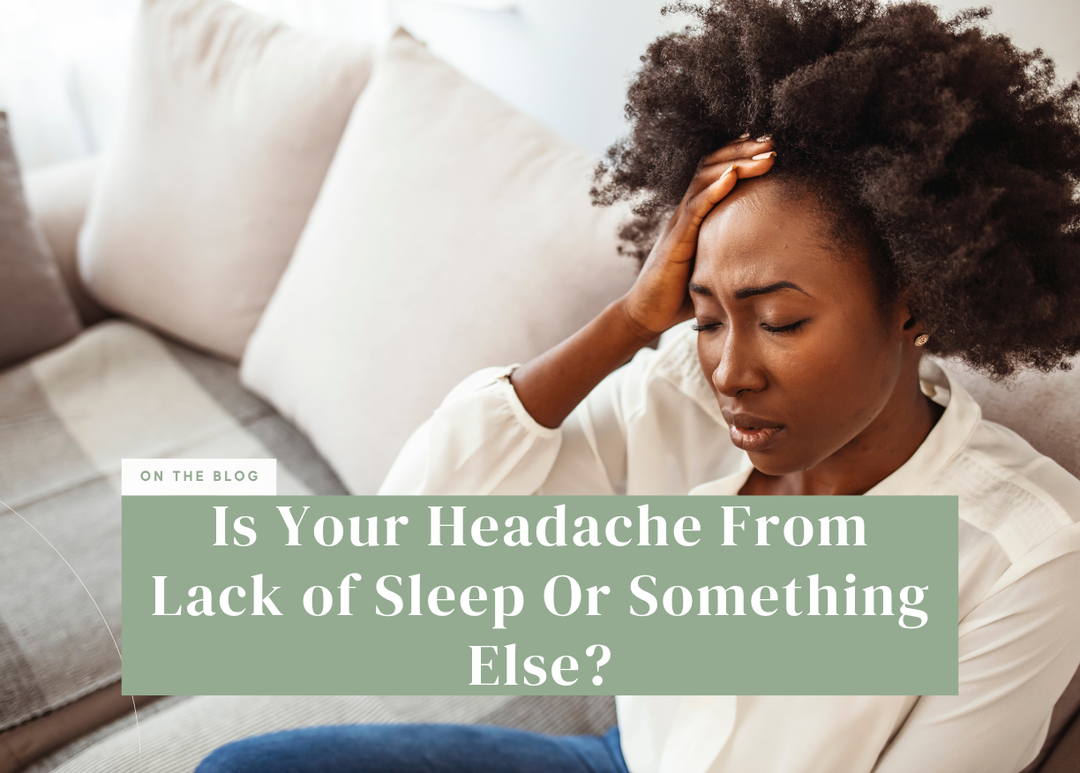 Woman sitting on a sofa touching her forehead with a pained expression.