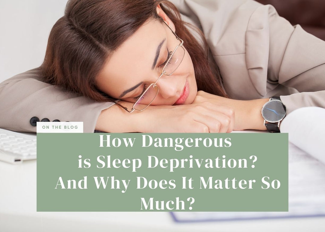 Woman wearing glasses slumping her head down onto her arms at a office desk.