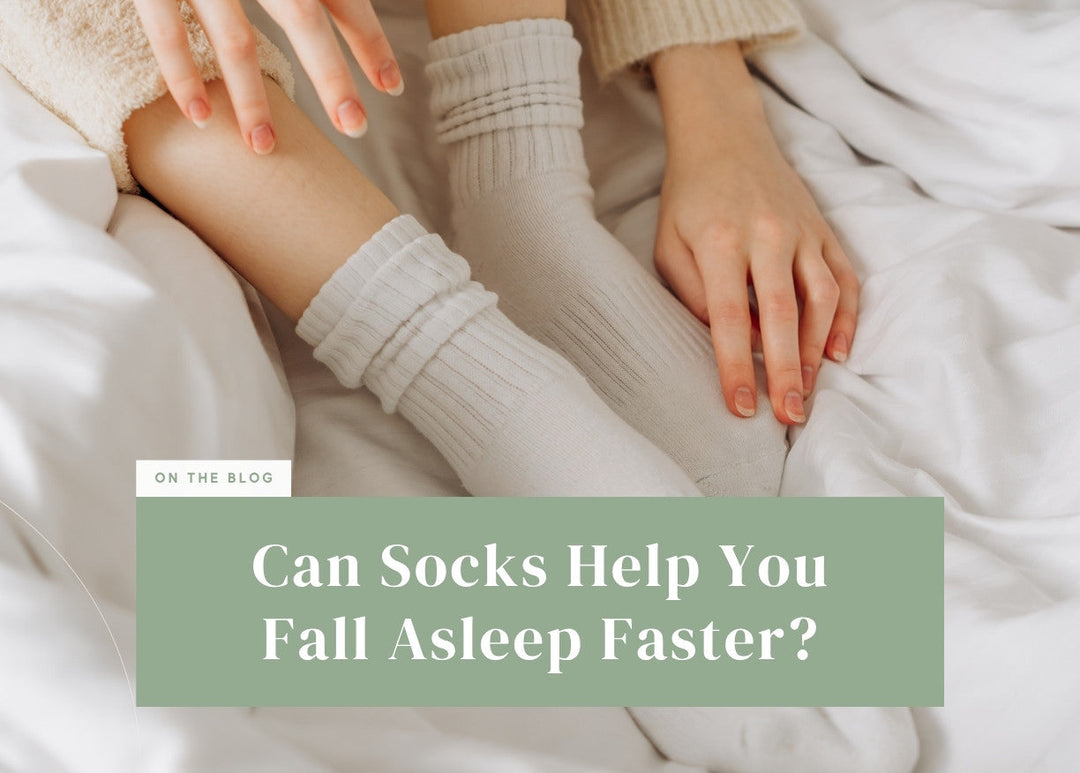 Person sitting in bed wearing soft white ribbed crew socks on clean white sheets.