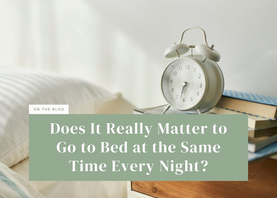 Vintage white alarm clock resting on a wooden nightstand next to white bedding.