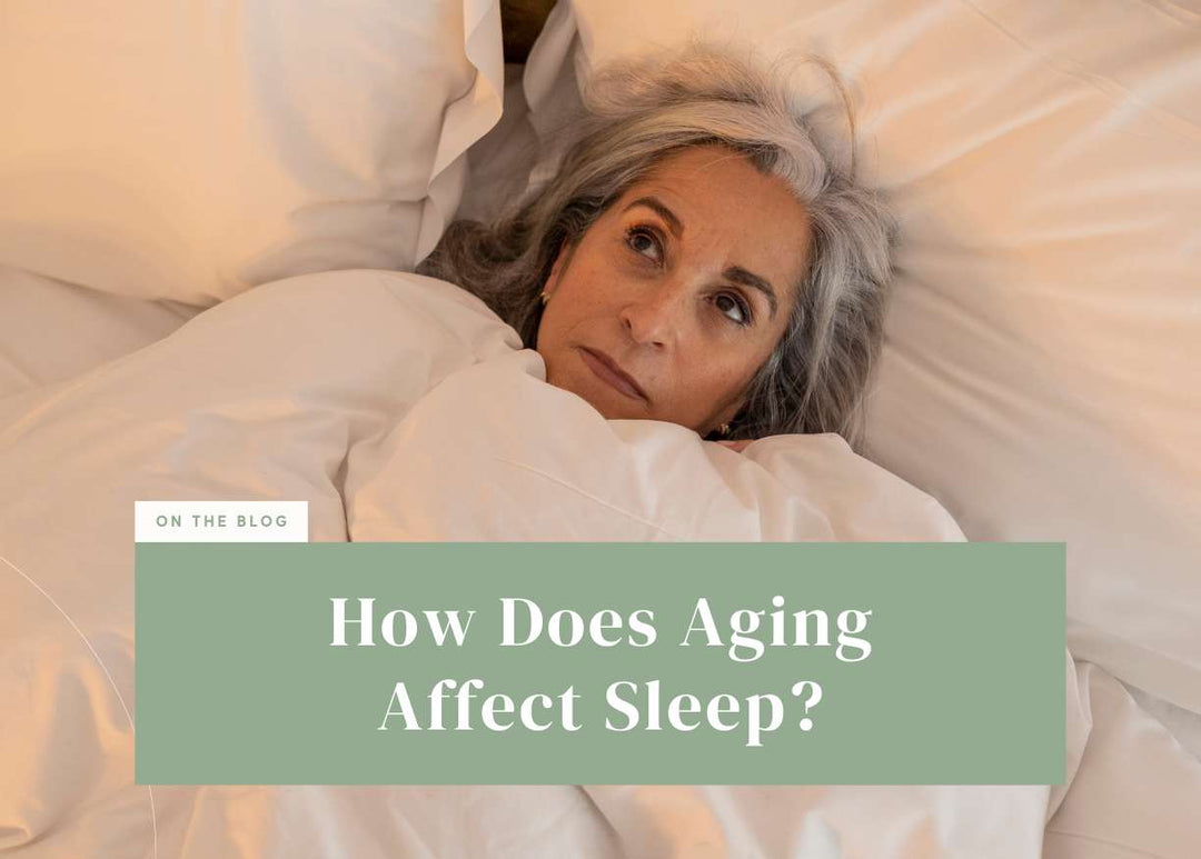 Older woman with grey hair lying in bed under white bedding and looking upward thoughtfully.