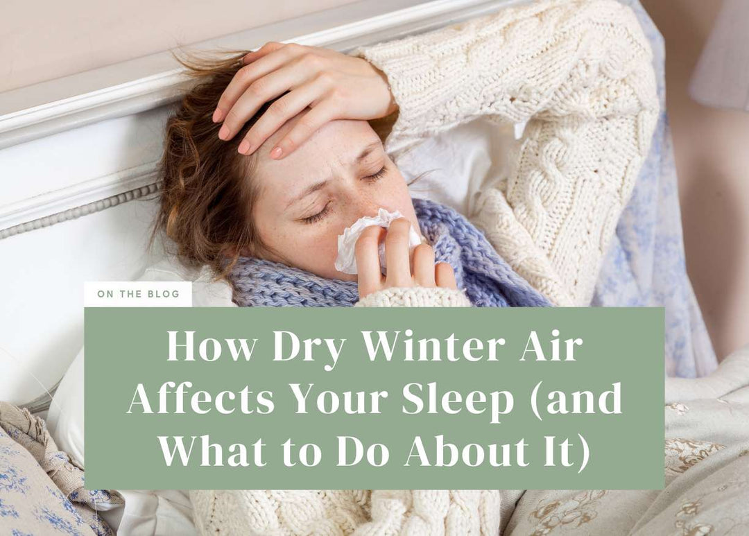 Woman lying in bed wearing a knit sweater and scarf while blowing her nose with a tissue.
