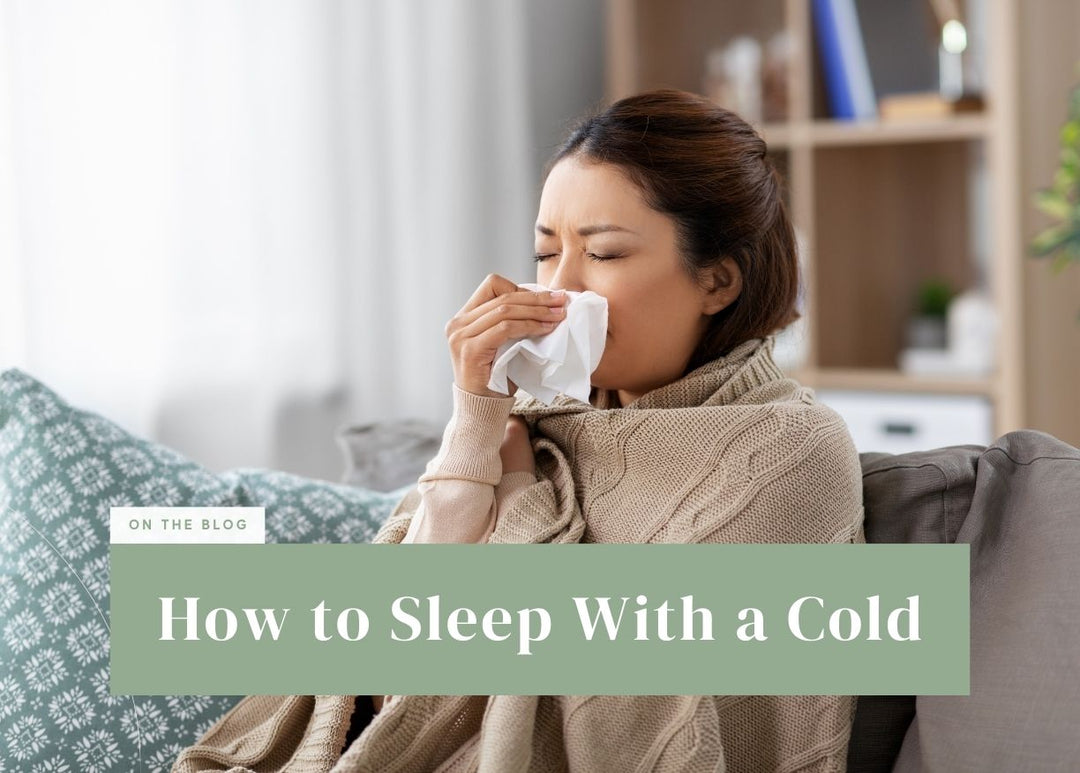 Woman wrapped in a cozy blanket blowing her nose with a facial tissue.