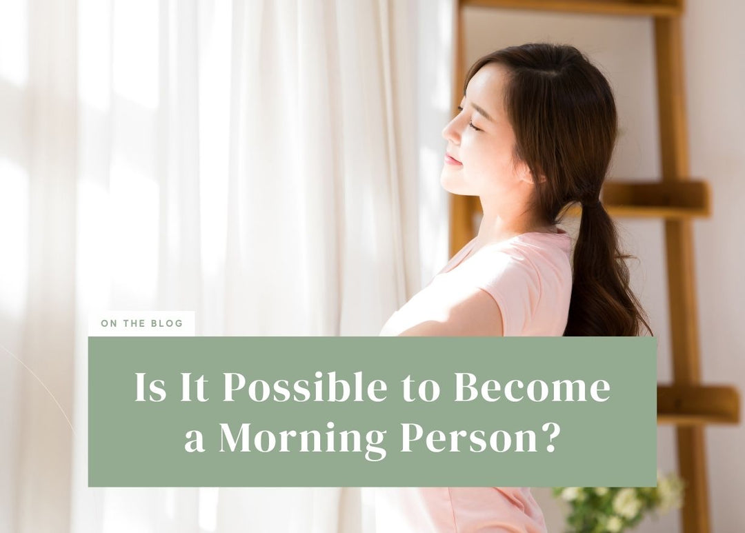Woman standing by a window taking a deep breath in the morning light.