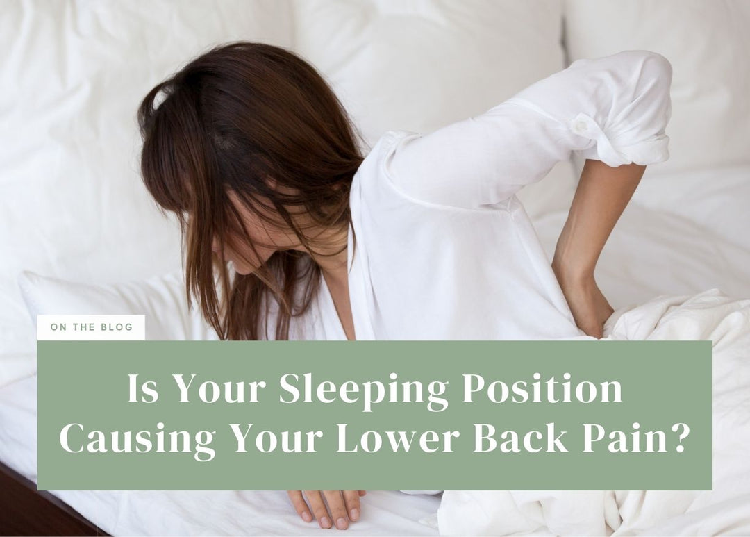Woman holding her lower back in discomfort while getting out of bed.