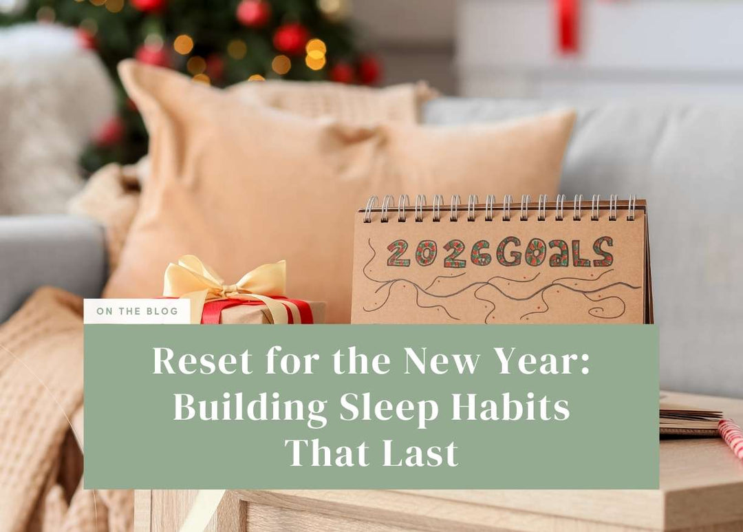 Spiral-bound notebook with "2026 GOALS" handwritten on its cover resting on a wooden table near a wrapped gift box.