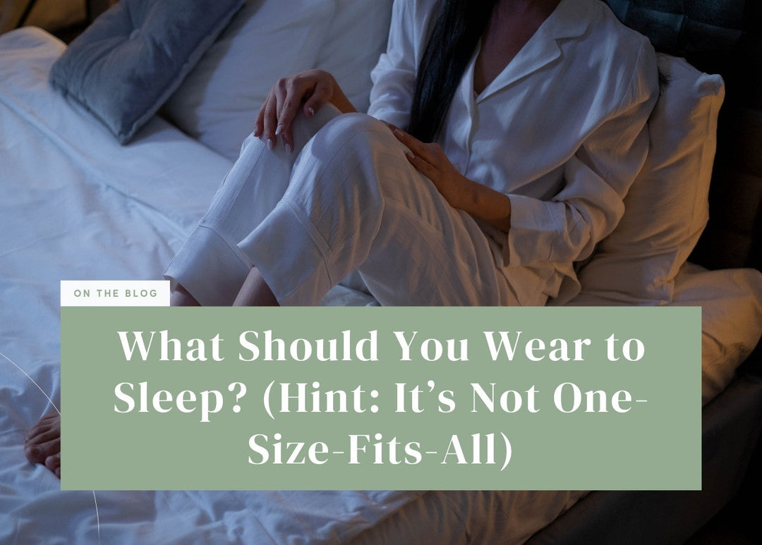 Person wearing white button-up pajamas sitting comfortably on a white bed.