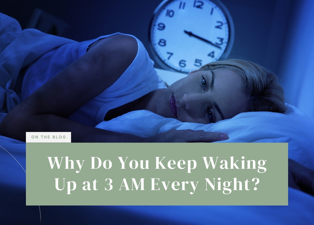 Woman lying awake in bed under blue night light with a clock in the background.