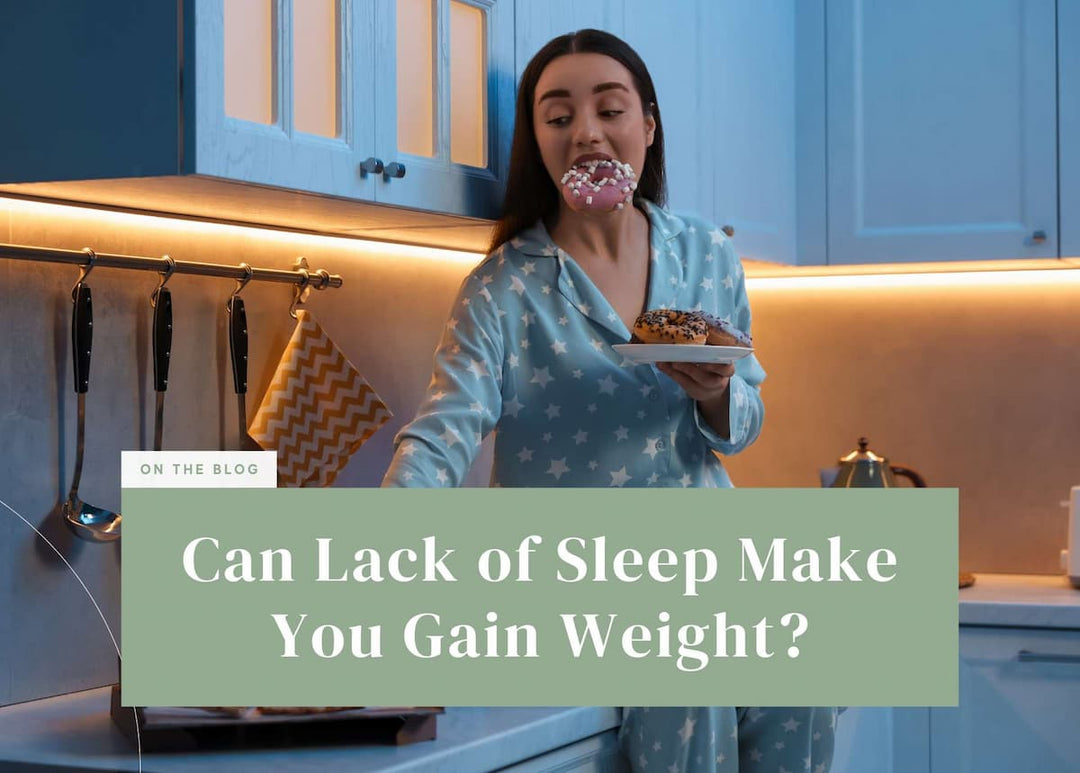 Woman in pajamas eating a donut late at night in her kitchen.