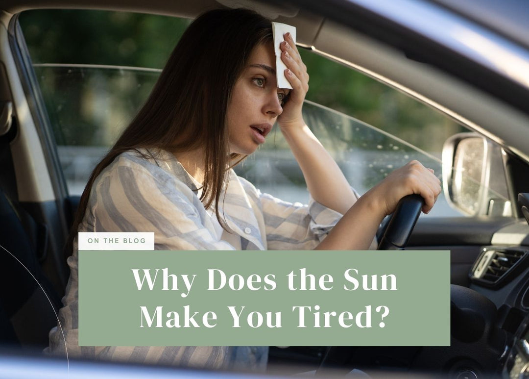 Woman wiping sweat from her forehead while sitting in the driver's seat of a car.